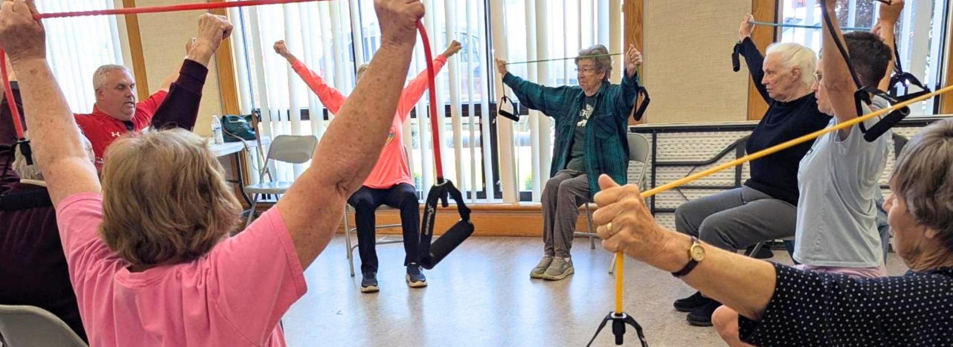 Older adults sitting in a circle stretching arms overhead